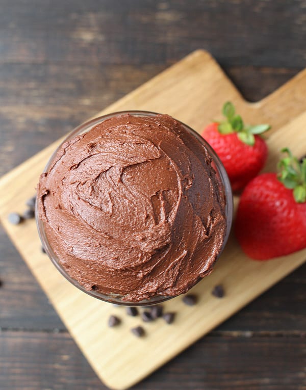 Paleo Chocolate Frosting  in a jar on a wooden cutting board. 